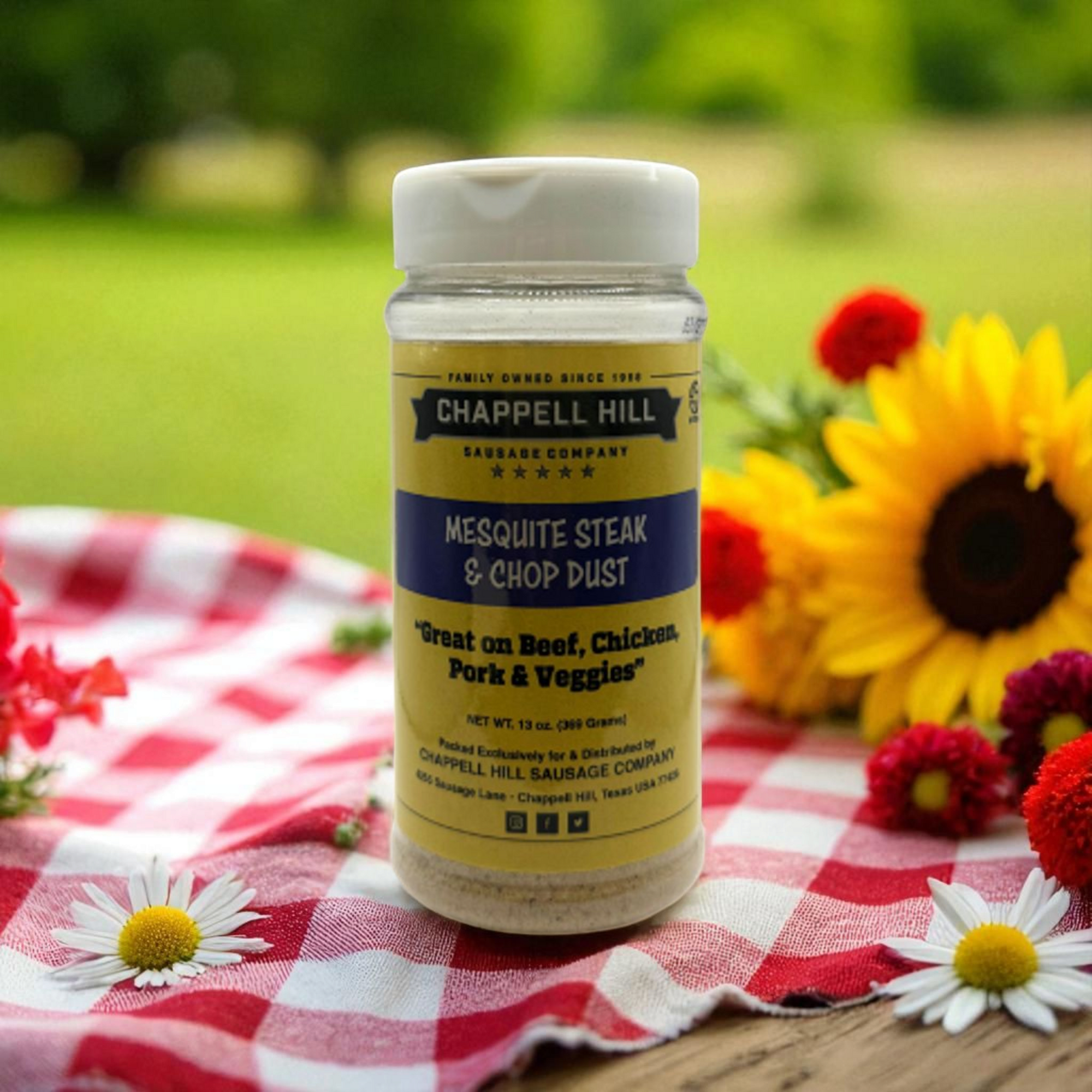Chappell Hill Mesquite Steak & Chop Dust seasoning bottle on a picnic blanket with flowers