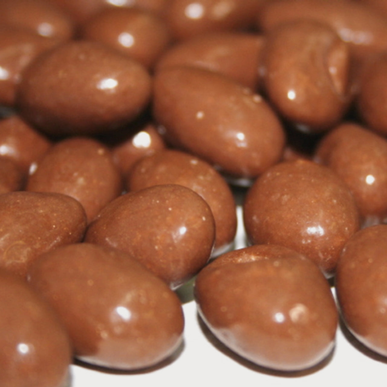 Close-up of chocolate-covered almonds on a white background