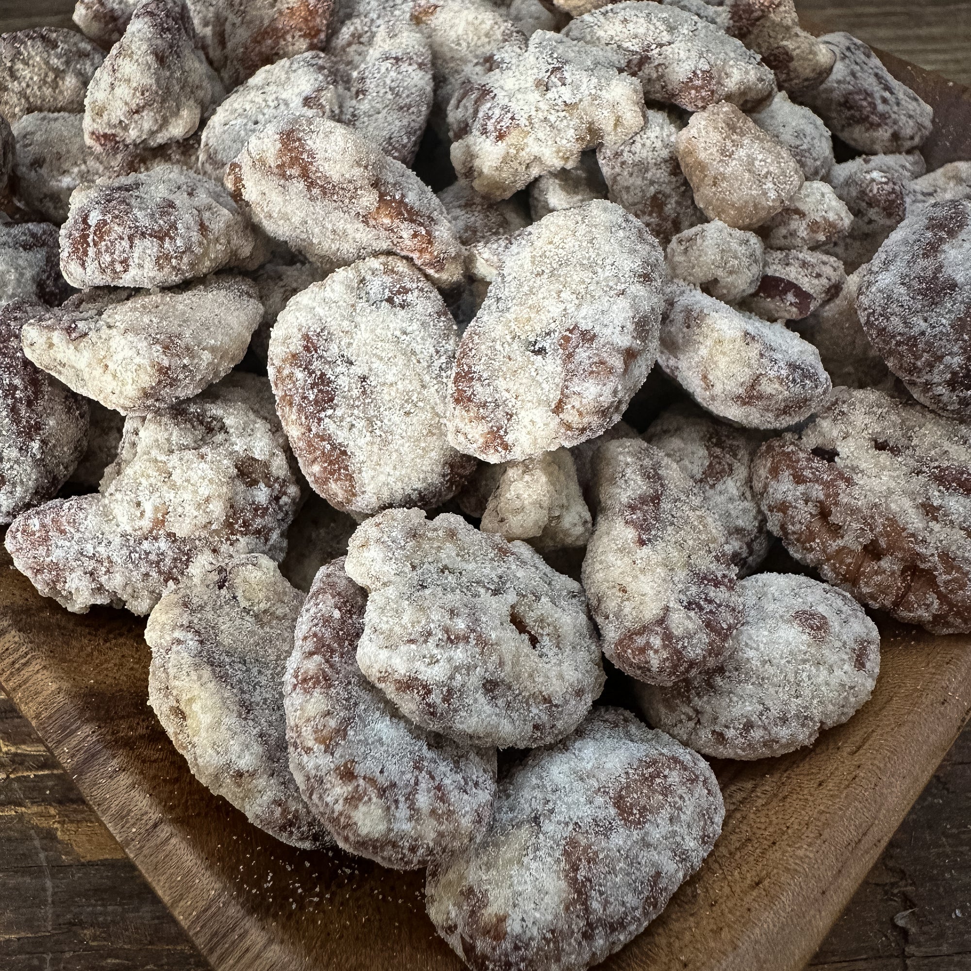 Pecans coated in a sugar mixture on a wooden board