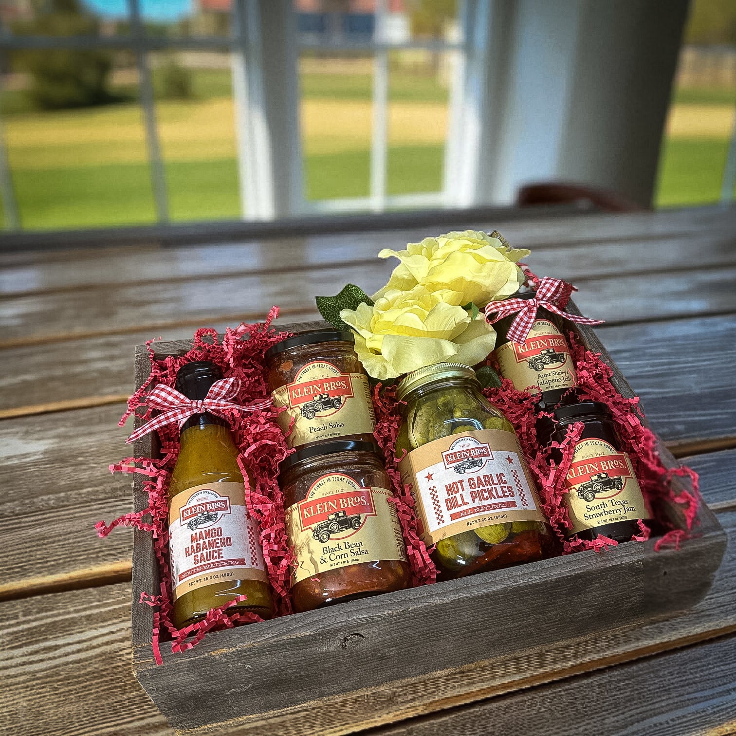 Wooden gift box with pickling supplies and a yellow flower on a wooden surface.