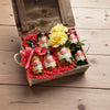 Gift set with mini bottles and a yellow flower in a wooden box on a wooden surface